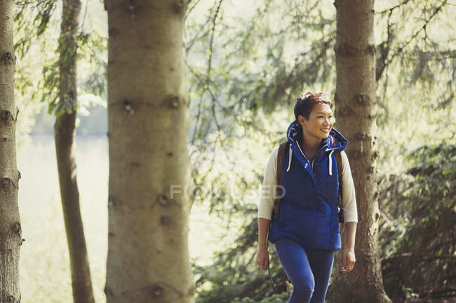 Усміхнена жінка гуляє в лісі — стокове фото