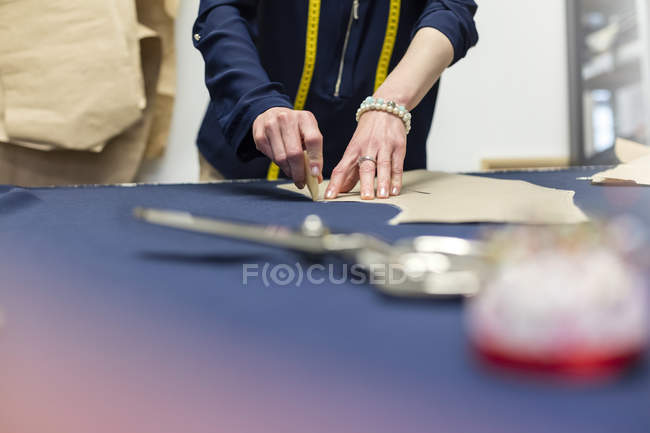 Female tailor marking fabric with pattern in menswear workshop — Stock Photo