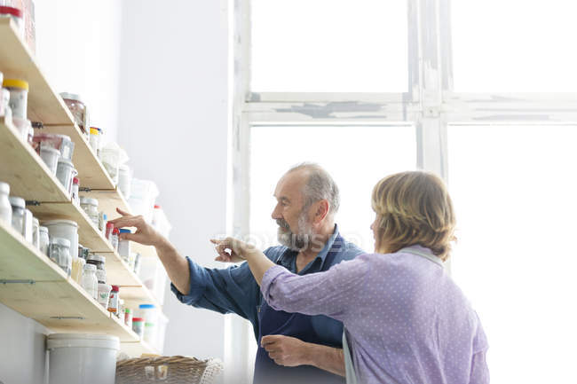 Man and woman browsing art supplies on shelves in art studio — Stock Photo