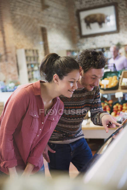 Couple shopping at display case in market — Stock Photo