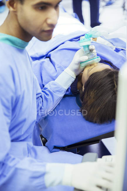 Anesthésiste tenant un masque à oxygène sur le visage des patients en salle d'opération — Photo de stock