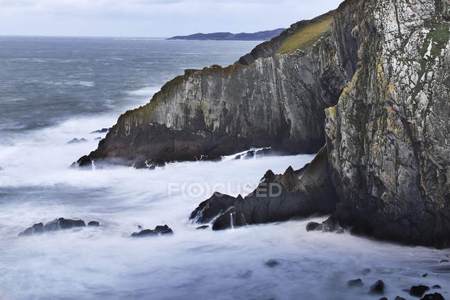 Ocean and craggy cliffs, Devon, Reino Unido - foto de stock
