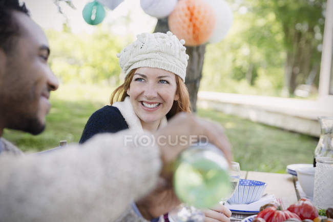 Smiling couple pouring wine at patio lunch table — Stock Photo