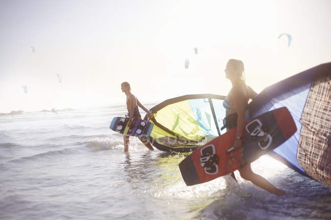 Coppia che cammina nel surf con attrezzatura da kiteboard — Foto stock