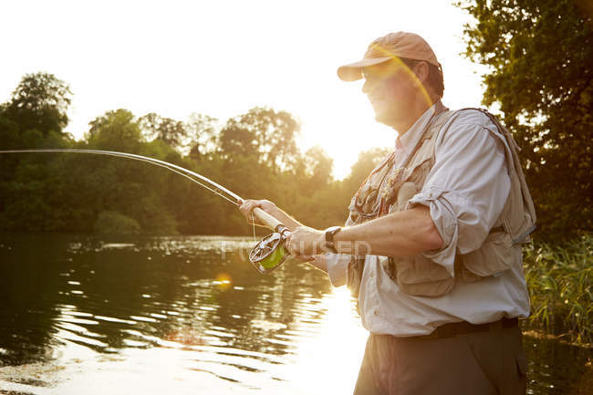 Uomo anziano pesca a mosca al lago estivo — Foto stock