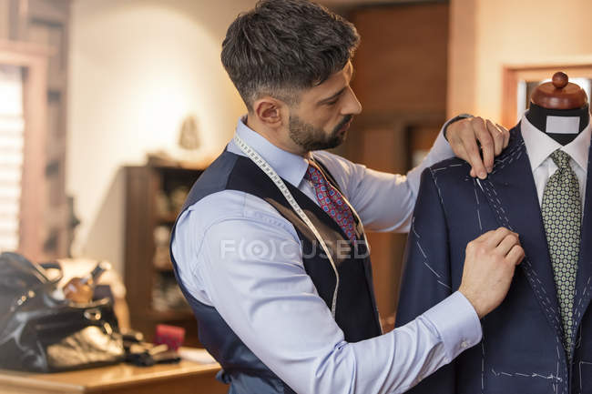 Tailor adjusting suit on dressmakers model in menswear shop — Stock Photo