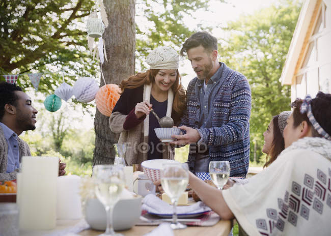 Casal servindo almoço para amigos na mesa do pátio — Fotografia de Stock