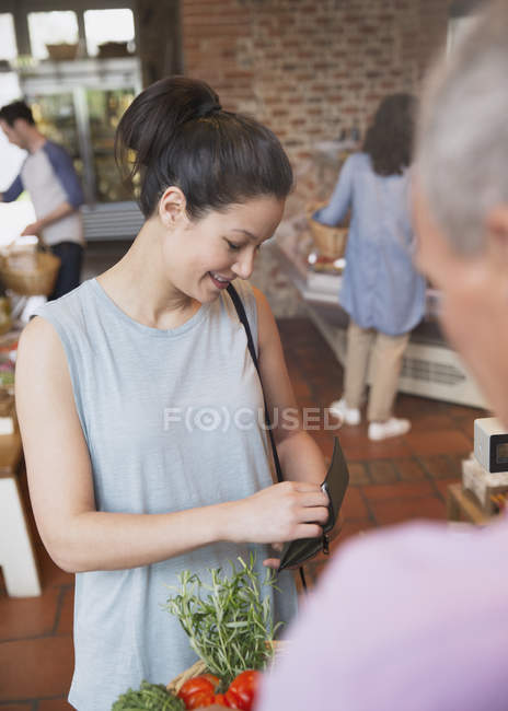 Женщина с кошельком платит в кассе продуктового магазина — стоковое фото