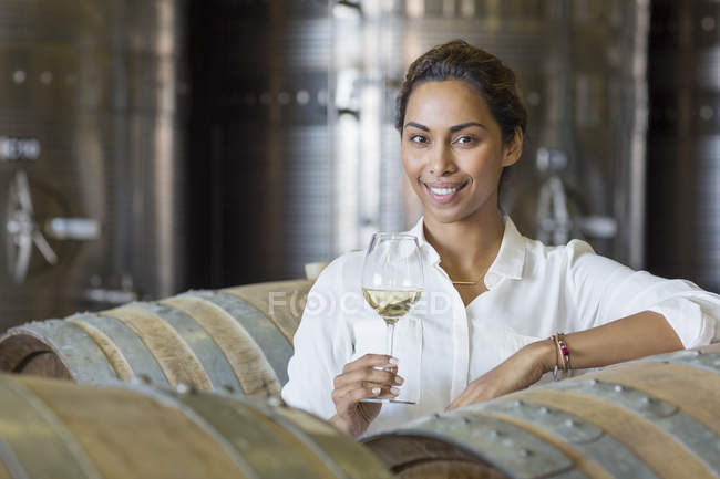 Portrait confident vintner drinking white wine in winery cellar — Stock Photo