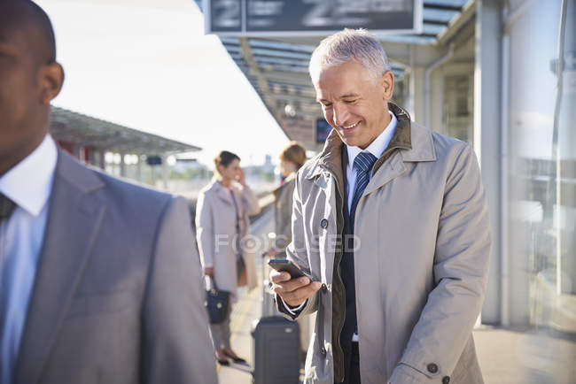 Uomo d'affari sms con il cellulare fuori aeroporto — Foto stock