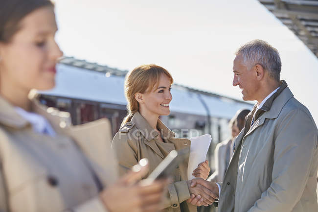 Empresário e empresária aperto de mão na ensolarada plataforma da estação ferroviária — Fotografia de Stock