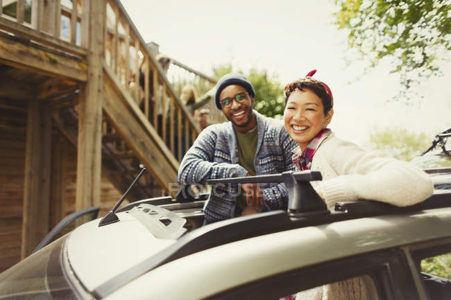 Portrait smiling couple standing in car sunroof outside cabin — Stock Photo