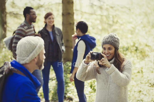 Woman photographing man hiking with camera in woods — Stock Photo