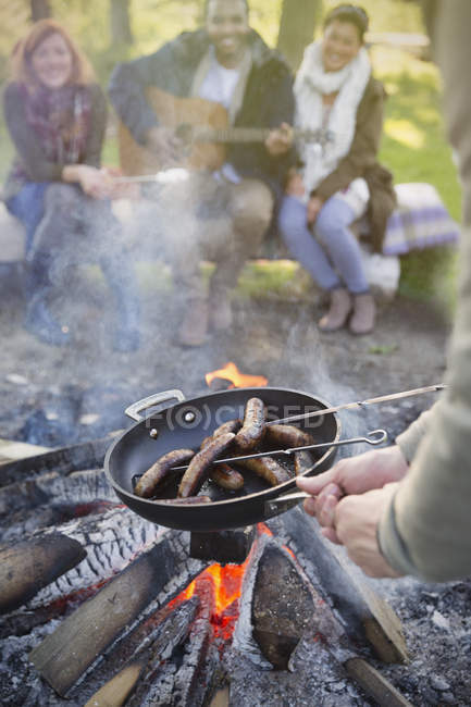 Amis cuisson hot-dogs sur le feu de camp — Photo de stock