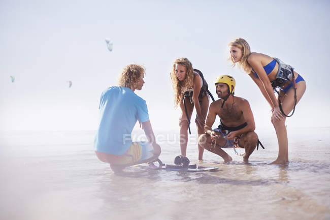 Homme enseignant amis kiteboard sur la plage ensoleillée — Photo de stock