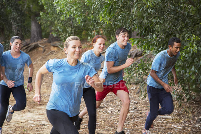 Equipo sonriente corriendo en la carrera de obstáculos del campamento de arranque - foto de stock