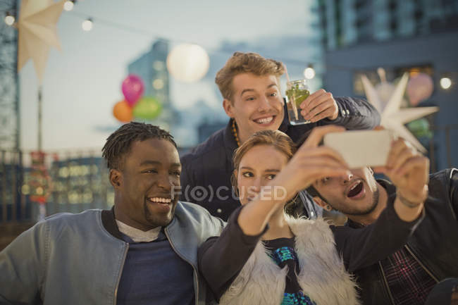 Amigos adultos jóvenes tomando selfie en la fiesta en la azotea - foto de stock