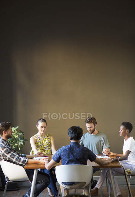 Serene casual business people holding hands with eyes closed at office table — Stock Photo