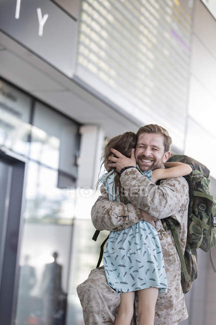 Hija saludo y abrazo soldado padre en aeropuerto - foto de stock