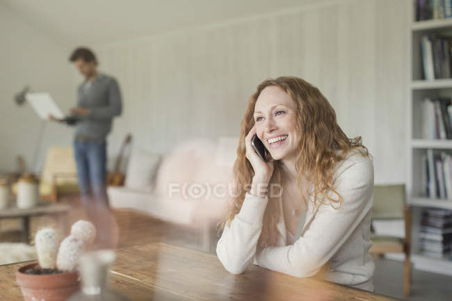 Sorrindo mulher falando no celular na mesa de jantar — Fotografia de Stock