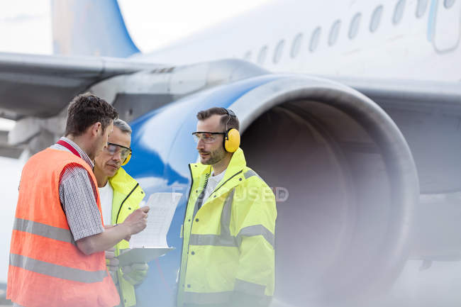 Air traffic control ground crew with clipboard next to airplane on tarmac — Stock Photo