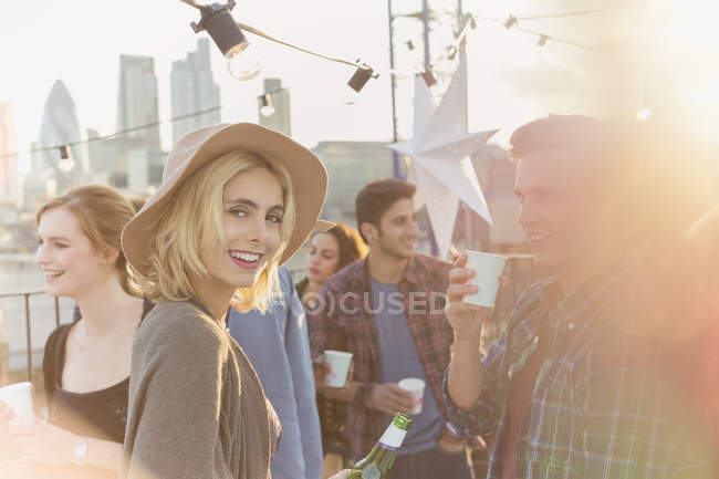 Portrait smiling young woman drinking beer at rooftop party — Stock Photo