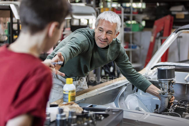 Father and son rebuilding classic car engine in auto repair shop — Stock Photo