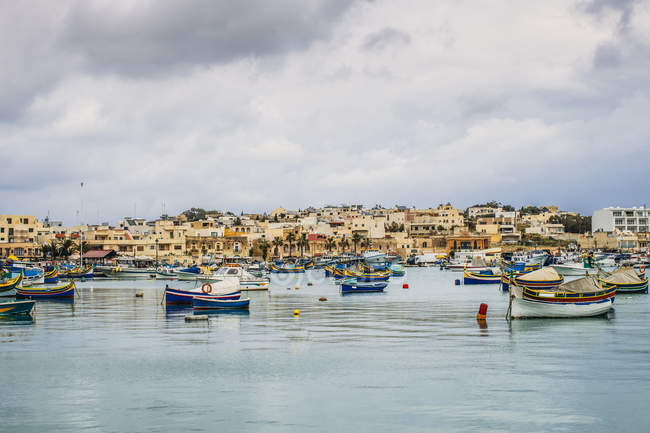 Barcos amarre fuera de la ciudad frente al mar, Marsaxlokk, Malta - foto de stock