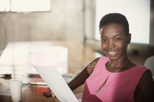 Retrato sorridente empresária com papelada no escritório — Fotografia de Stock