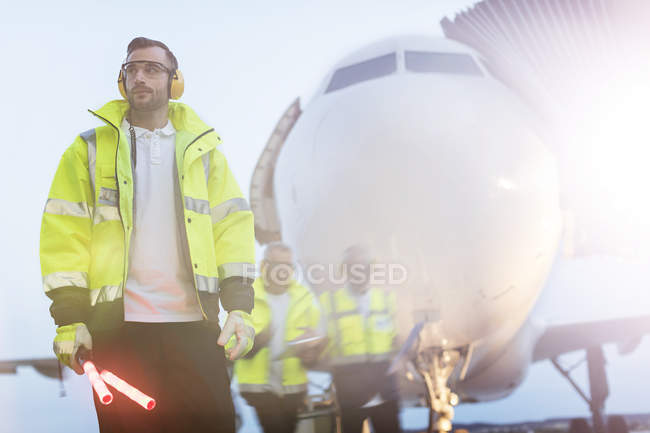 Air traffic controller standing in front of airplane on airport tarmac — Stock Photo
