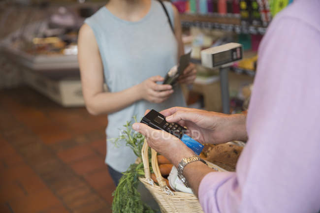 Verkäuferin im Lebensmittelgeschäft mit Kreditkartenautomat — Stockfoto