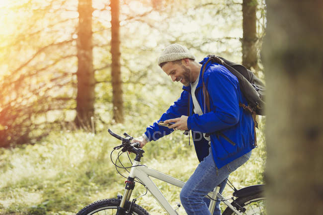 Чоловік гірський велосипедний текст з мобільним телефоном у лісі — стокове фото