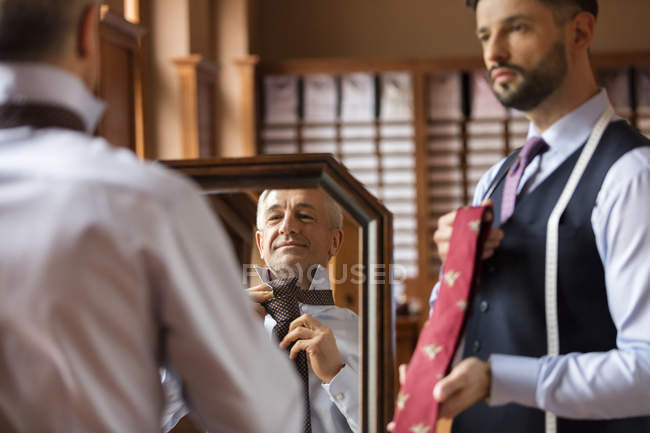 Кравець показ зв'язків з бізнесмен на дзеркало в магазин чоловічого одягу — стокове фото