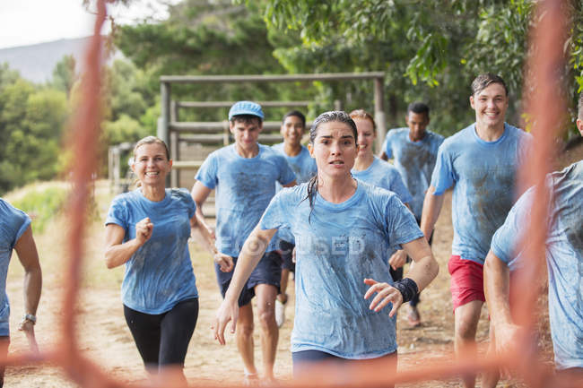 Team running in rain on boot camp obstacle course — Stock Photo