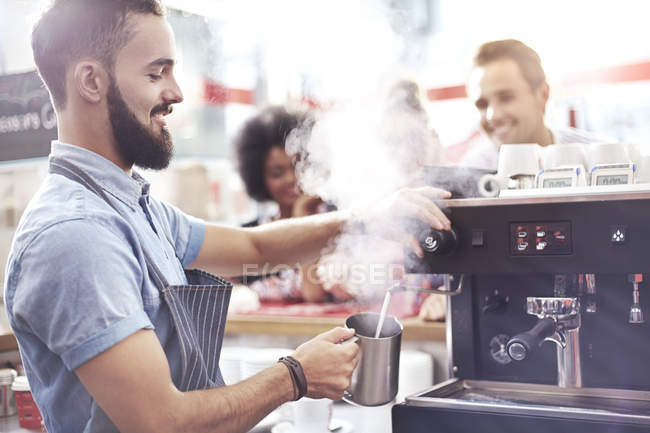 Barista steaming milk in modern cafe — Stock Photo