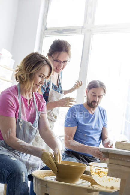 Professor orientando casal maduro usando roda de cerâmica no estúdio — Fotografia de Stock