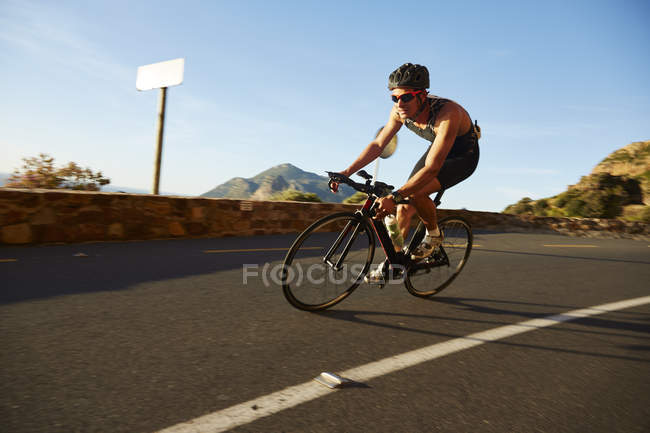 Ciclismo masculino en esquina soleada - foto de stock