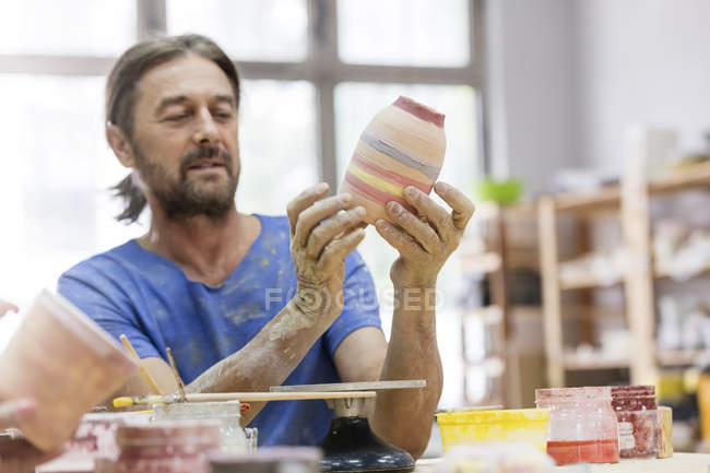 Mature man painting pottery vase in studio — Stock Photo