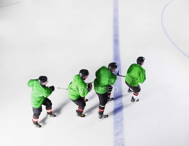 Équipe de hockey en uniforme vert patinant d'affilée sur glace — Photo de stock
