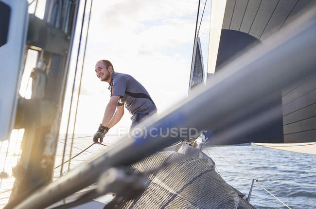 Smiling man sailing holding rigging on sailboat — Stock Photo