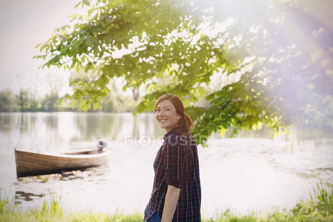 Retrato mulher sorridente ao lado do lago ensolarado — Fotografia de Stock