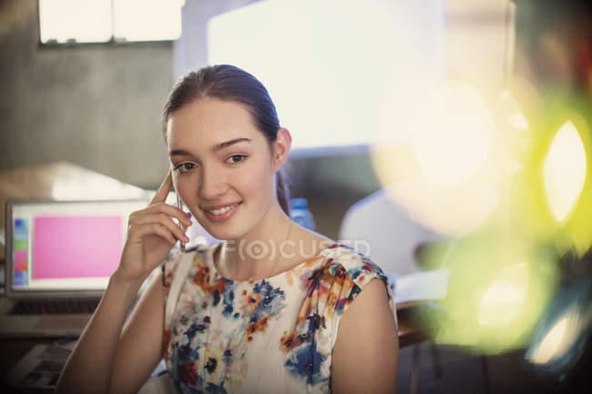 Smiling businesswoman talking on cell  phone in office — Stock Photo