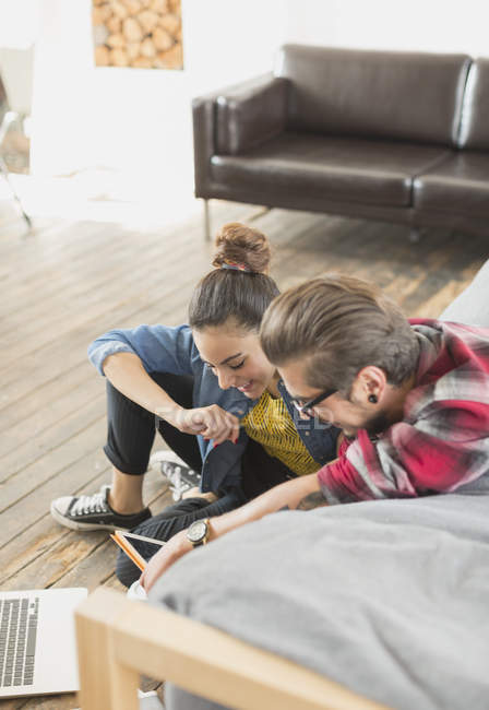 Молодая пара с помощью ноутбука и цифрового планшета в квартире — стоковое фото