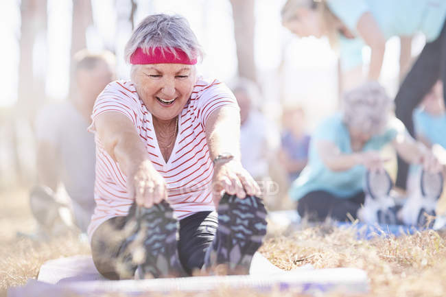 Sorrindo mulher idosa alongamento na aula de ioga — Fotografia de Stock