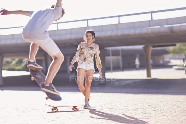 Мальчик и девочка катаются на скейтборде в солнечном скейт-парке — стоковое фото