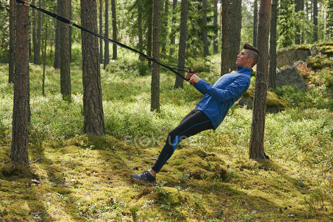 Corredor usando banda de resistência na árvore na floresta — Fotografia de Stock