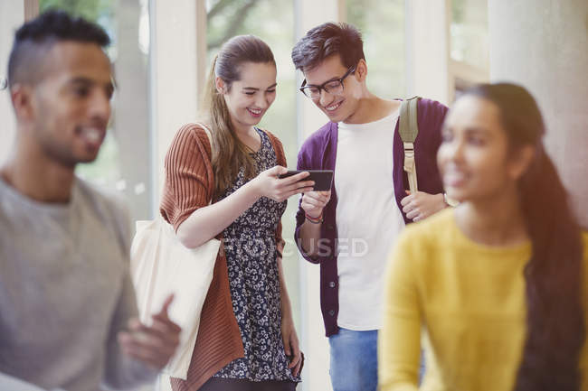 Estudiantes universitarios enviando mensajes con teléfono celular - foto de stock