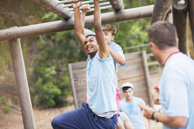 Man crossing monkey bars on boot camp obstacle course — Stock Photo