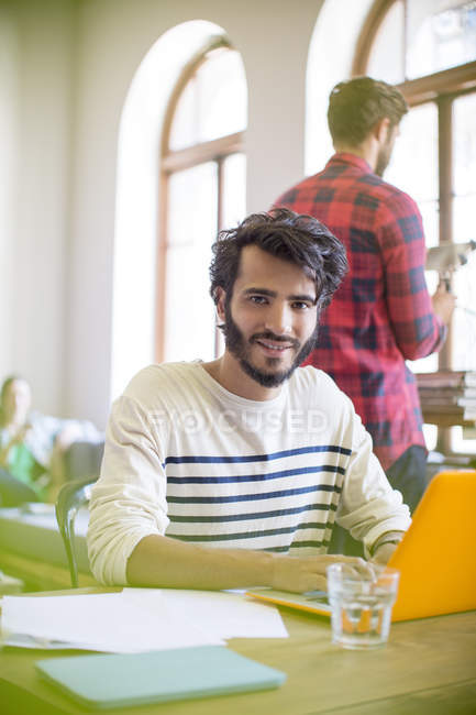Retrato confiante empresário casual usando laptop no escritório — Fotografia de Stock