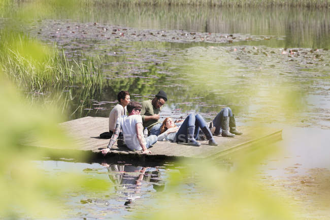 Freunde liegen und entspannen auf sonnigem Steg am Seeufer — Stockfoto